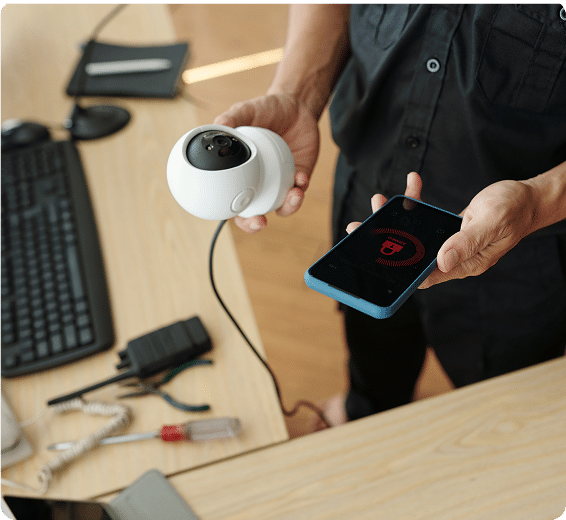person holding a web cam in one hand and a cell phone in the other (active monitoring)